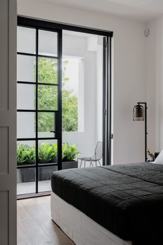 a bed sitting in a bedroom next to a sliding glass door with plants on it