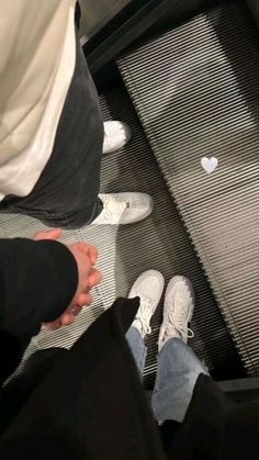 two people standing at the bottom of an escalator with their feet in the air