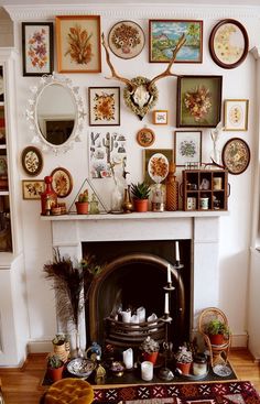 a living room filled with lots of pictures on the wall and a fire place in front of it