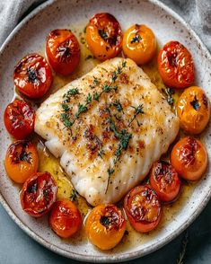 a white plate topped with fish and tomatoes