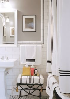 a white bathroom with black and white tile on the floor, shower curtain, sink, and towel rack