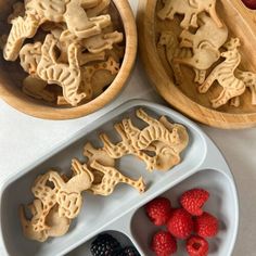 three trays filled with cookies and raspberries on top of a white table