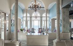 an elegant dining room with chandelier and chairs in front of large windows that look out onto the ocean