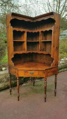 an old wooden hutch with shelves and drawers on the top, in front of some trees