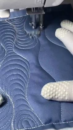 someone is using a sewing machine to sew something on a blue piece of cloth