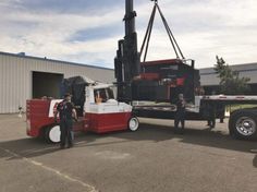 two men standing next to a truck with a crane on it's flatbed