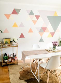 a dining room table with white chairs and colorful wallpaper