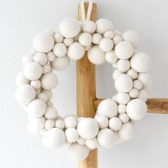 a wooden stick holding a white wreath on it's side with balls attached to it