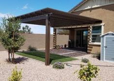 an outside view of a house with a pergolated roof and landscaping in the foreground