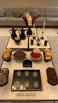 a table topped with cakes and desserts on top of a white tablecloth covered floor