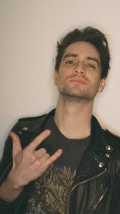 a man wearing a black leather jacket and holding his hand up