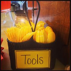 a basket filled with lots of yellow objects on top of a table next to a sign