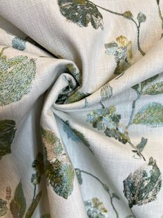 a close up view of a white fabric with green and blue flowers on the side