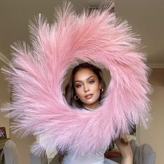 a woman in a white dress is holding a large pink furry object over her head