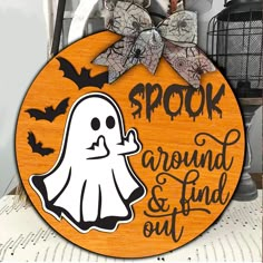 a wooden sign that says spook around and find out with a ghost on it