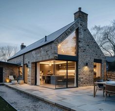 a brick house with an open patio and dining area in the back yard at dusk