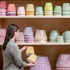 a woman is looking at colorful lamps in a room with shelving full of them