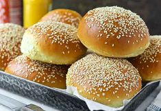 a bunch of buns sitting on top of a pan filled with sesame seed bread