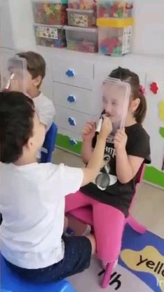 two children sitting on the floor playing with an object in front of them and another child standing behind them