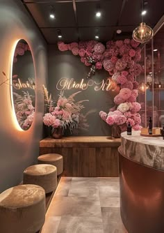 the interior of a beauty salon with flowers on the wall and stools in front