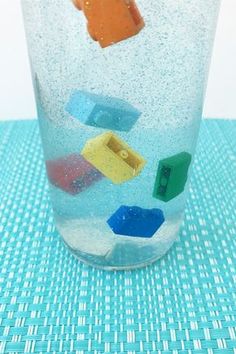 a glass filled with lots of different colored objects on top of a blue table cloth