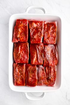 meat cubes in a white casserole dish on a marble countertop top