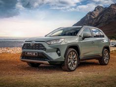 the new toyota rav is parked in front of some mountains and water on a cloudy day