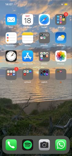 an iphone screen with icons on it and the sun setting in the distance behind them