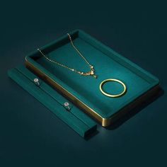 a green box with two necklaces and a ring on it