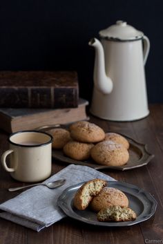 some cookies are sitting on a plate next to a tea pot and a cup of coffee