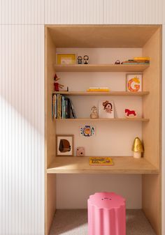 a pink stool sits in front of a bookshelf filled with children's toys