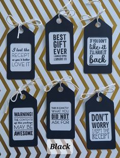 four black and white tags with sayings attached to them on a striped paper background