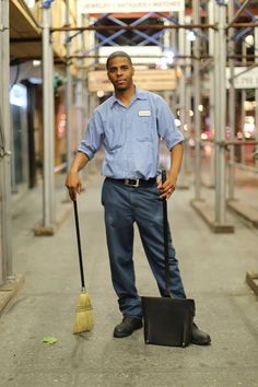 a man standing on the sidewalk with a broom and suitcase