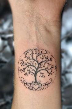 a tree tattoo on the wrist with leaves and branches around it, in black ink