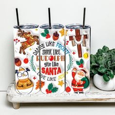 three tumblers sitting on top of a white shelf next to a potted plant