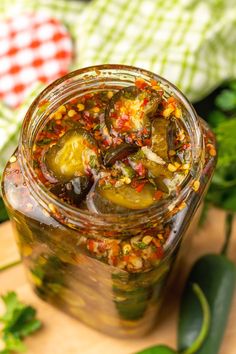 a jar filled with pickles and spices on top of a cutting board next to green leaves