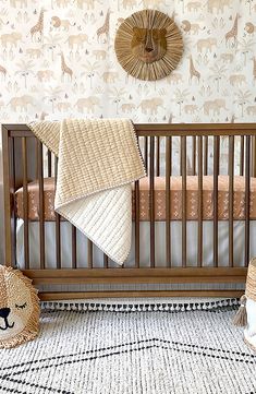 a baby crib with two stuffed animals on the floor next to it and a wall hanging above