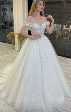 a woman in a white wedding dress posing for the camera with her hand on her hip