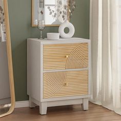 a white and wood dresser with a mirror on it's side next to a window