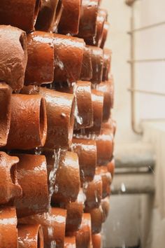 many brown pots are stacked on top of each other and have water running down them