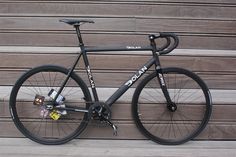 a black bike parked against a wooden wall