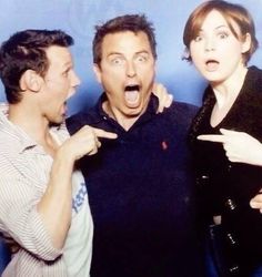 two men and a woman posing for the camera with their mouths wide open while pointing at something