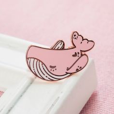 a pink whale pin sitting on top of a white box