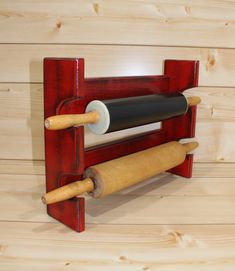 a red rack with two rolling pins and a roll of paper on top of it