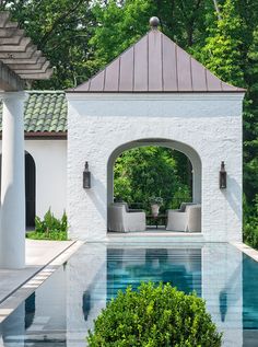 an outdoor swimming pool surrounded by columns and greenery in front of a gazebo