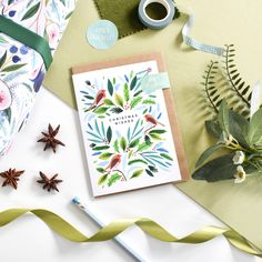 a greeting card with an image of birds and leaves on it next to some christmas decorations