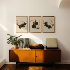 two framed pictures hang on the wall above a record player