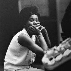 a black and white photo of a woman sitting on the floor with her hands to her mouth