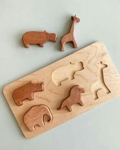 three wooden animals on a table next to some pieces of wood that are shaped like elephants and giraffes