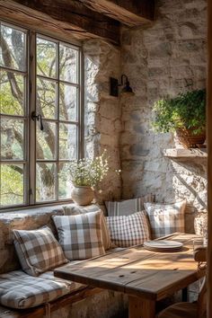 a wooden table sitting in front of a window next to a bench with pillows on it